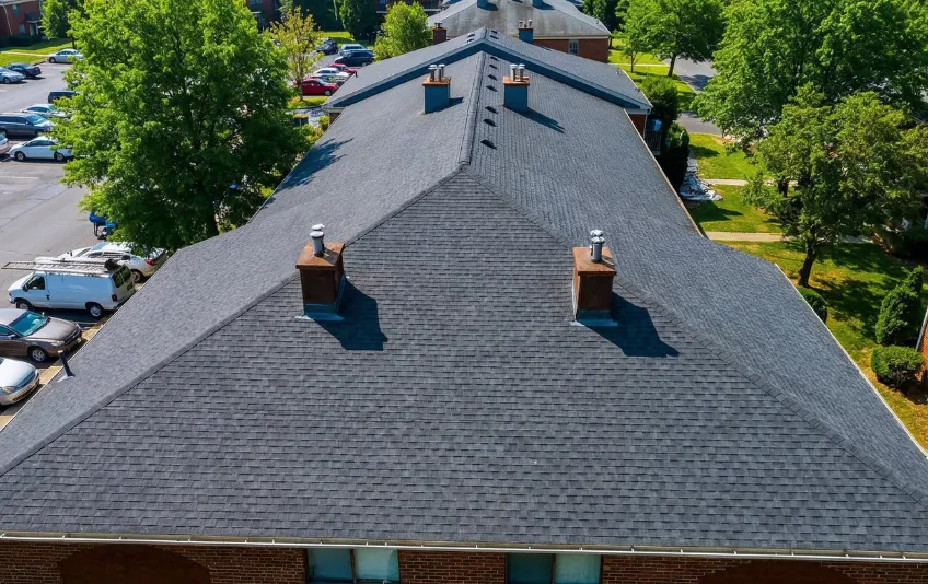 Roofing project in Los Angeles showing roof replacement with shingles installed on large residential building from aerial view